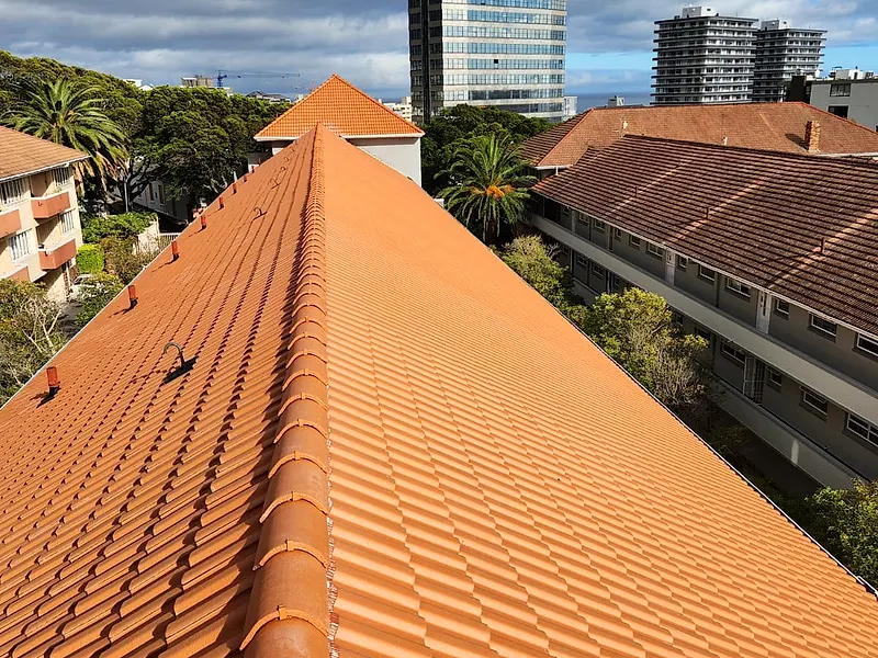 The same tiled roof at Middelhof Apartments after the work, bright terracotta with the Sea Point high-rises behind